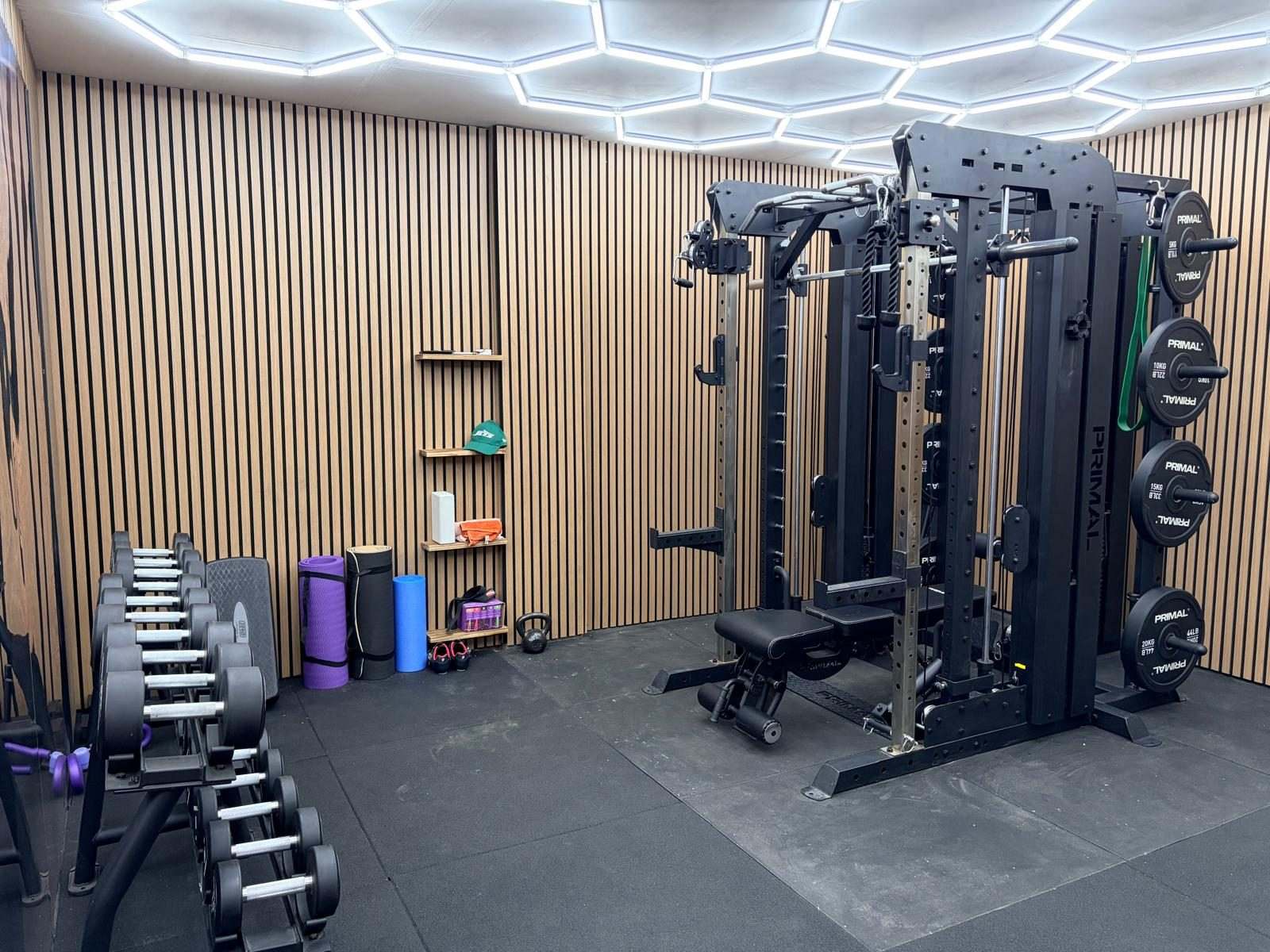Weights corner with a dumbbell rack, cage rack with plates and a lifting platform on heavy-duty rubber flooring